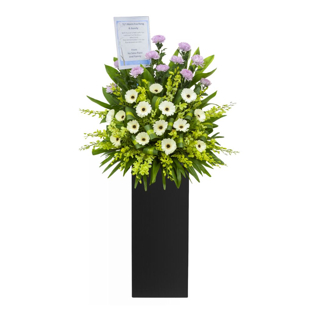 Floral condolences arrangement in a black pot on a white background