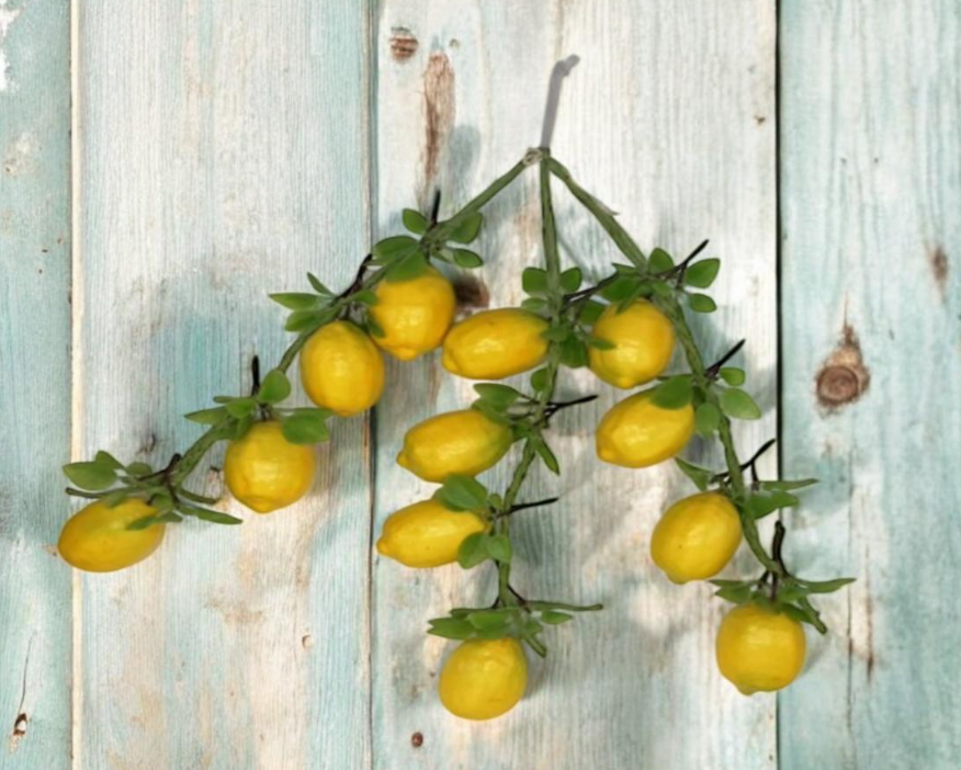 Hanging artificial yellow lemon string garland with green leaves, often used for kitchen or home decor.