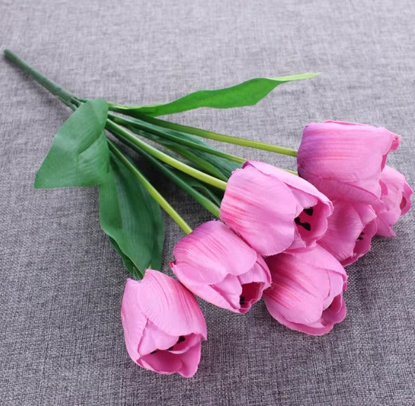 Artificial pink tulip bouquet with green leaves.