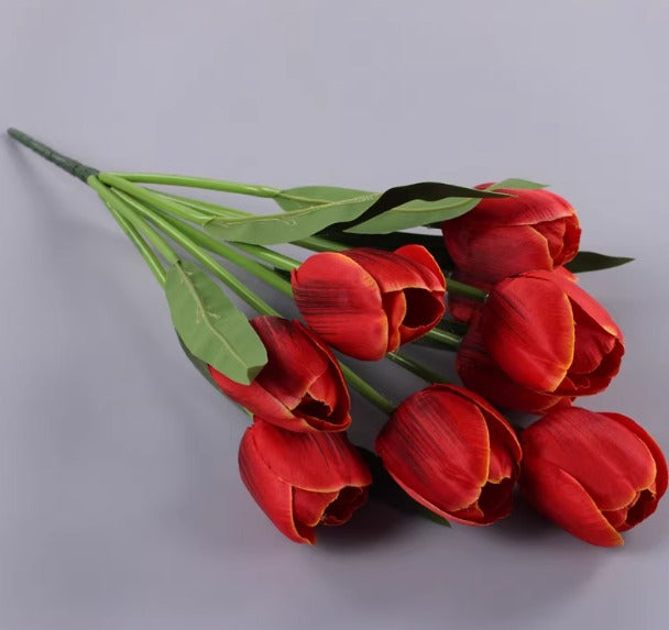 Artificial bright red tulip bouquet with green leaves.
