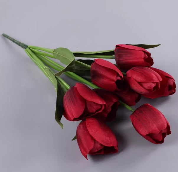 Artificial deep red tulip bouquet with green leaves.
