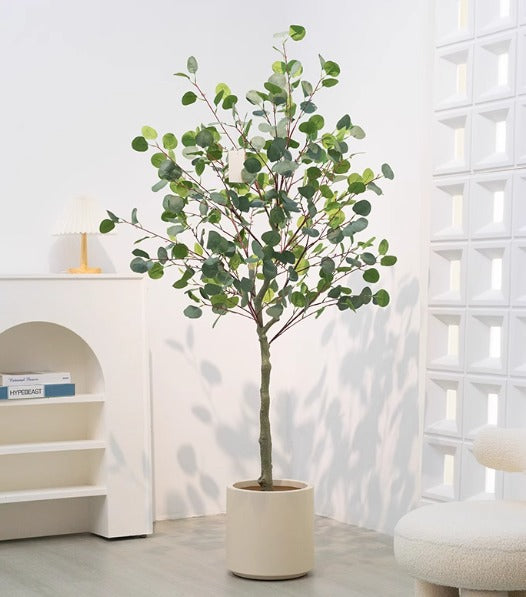 Potted artificial eucalyptus tree with round green leaves in a light beige pot, placed indoors.