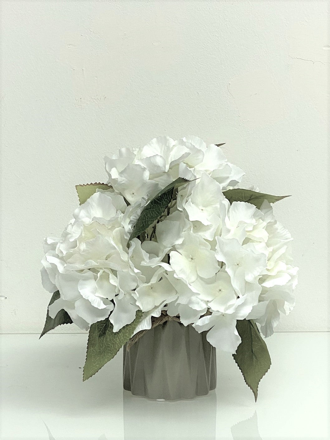 Artificial hydrangea flower in a pot by Alton Flowers, showcasing lush blue blooms and green foliage.