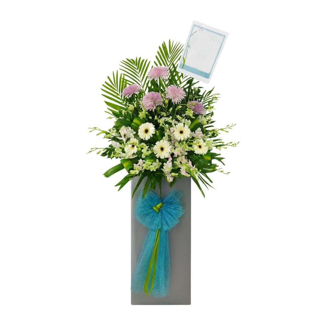 Floral condolences arrangement with a blue bow on a white background