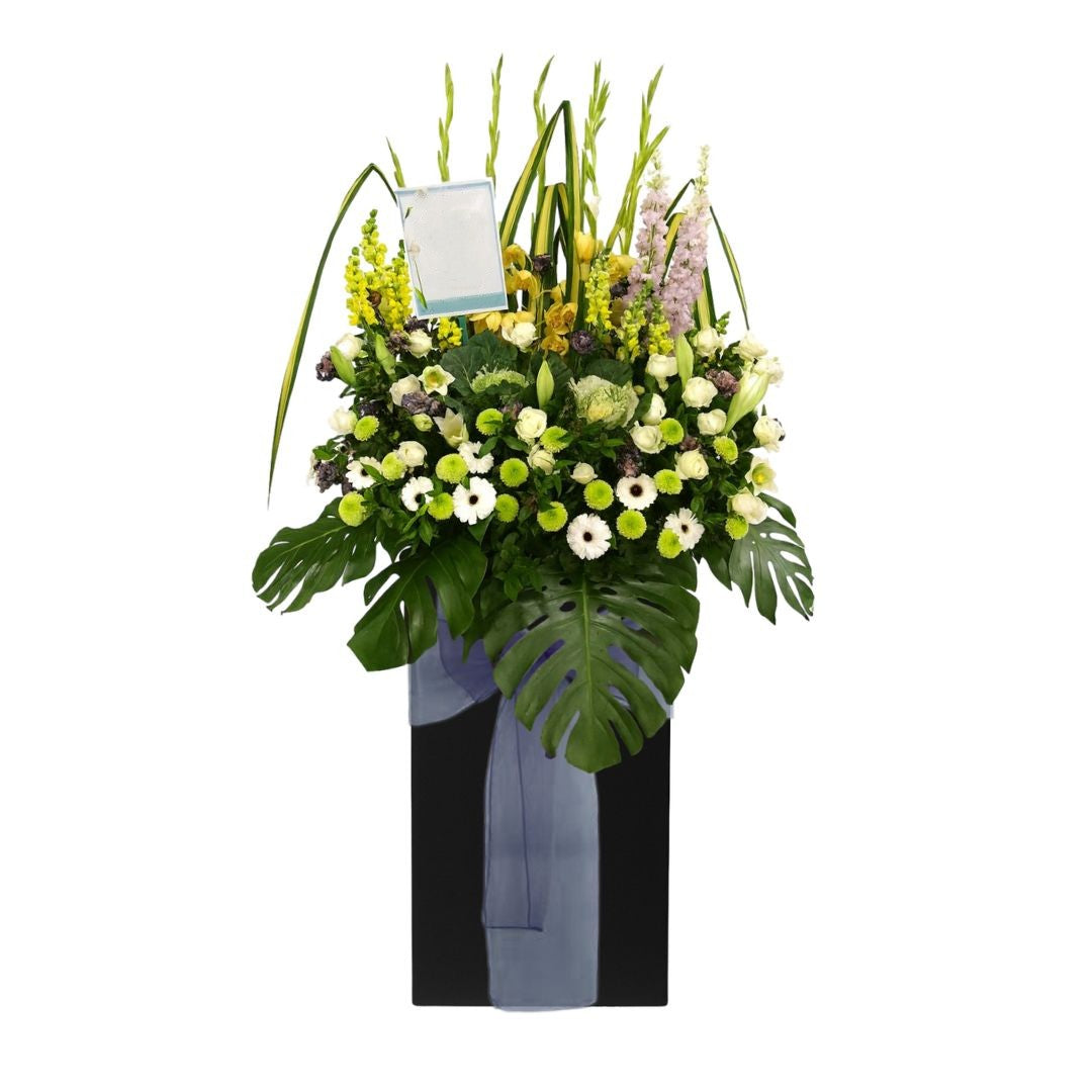 Floral condolences arrangement with a blue ribbon on a white background