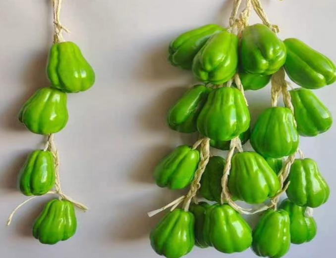 Hanging artificial green chayote squash decoration tied with twine.
