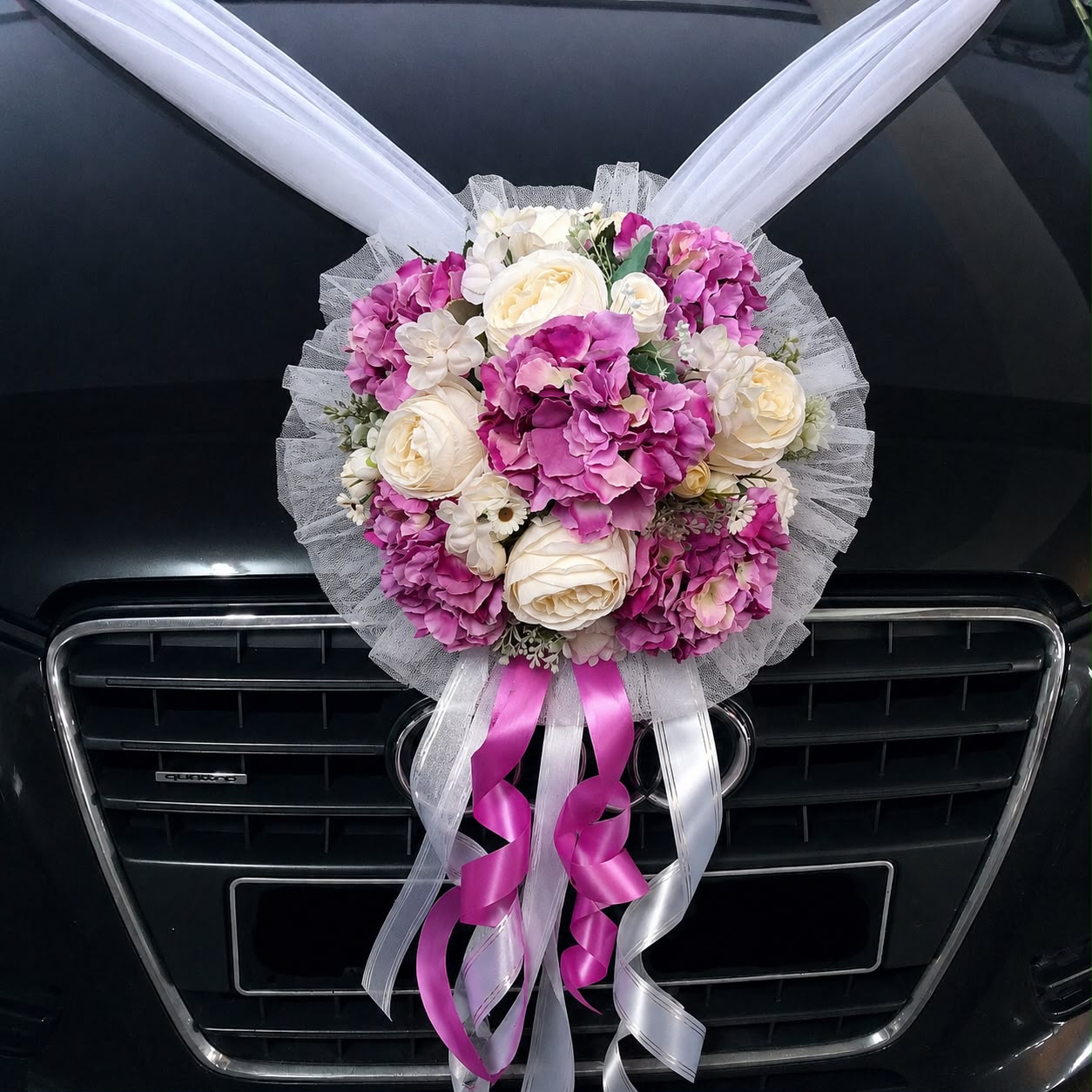 Elegant wedding car flowers by Alton Flowers featuring premium floral arrangements with white netting on a decorated vehicle.