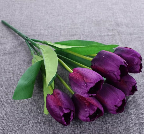 Artificial deep purple tulip bouquet with green leaves.