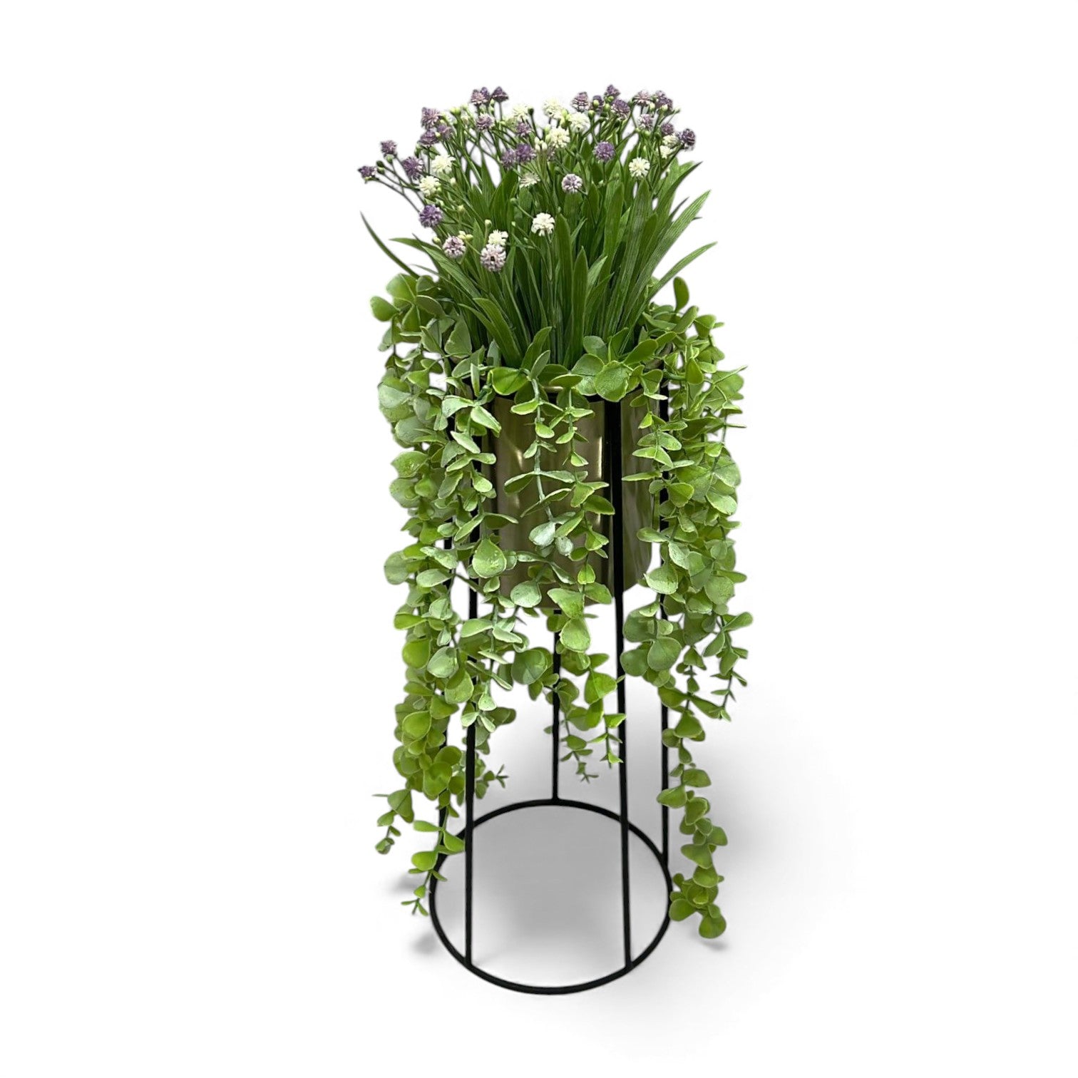 Artificial mixed flower arrangement with trailing eucalyptus and small white and purple flowers set in a gold-toned pot held by a black metal planter stand.
